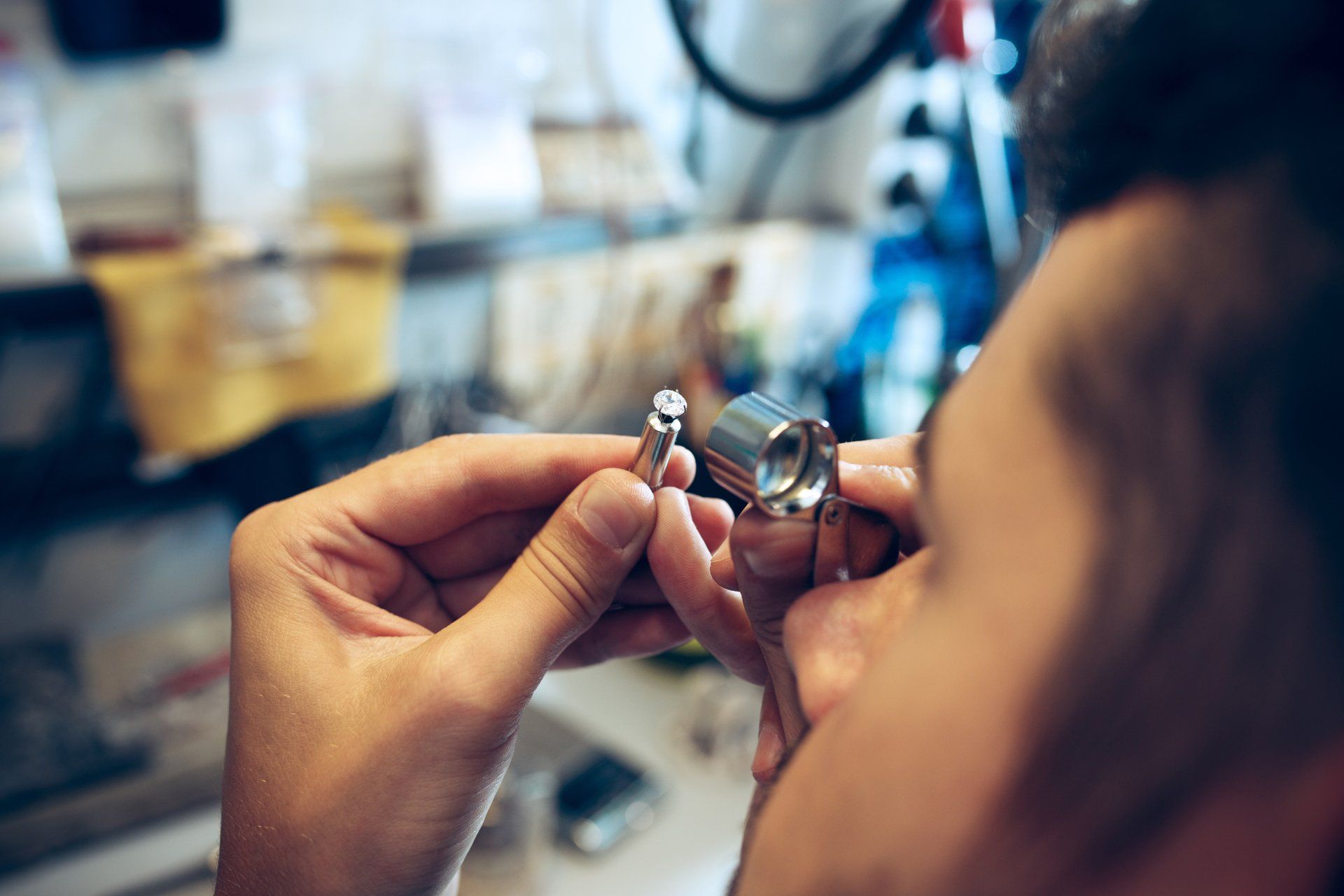 A man is looking at a pair of earrings through a magnifying glass.