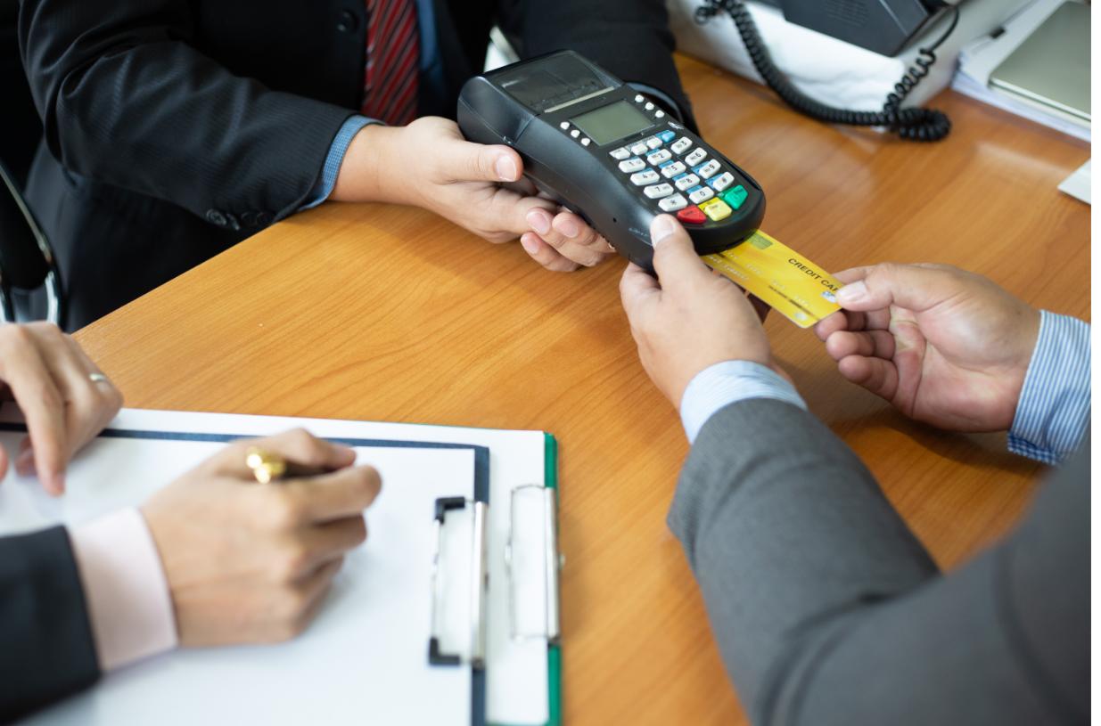 A man is using a credit card machine to pay another man.