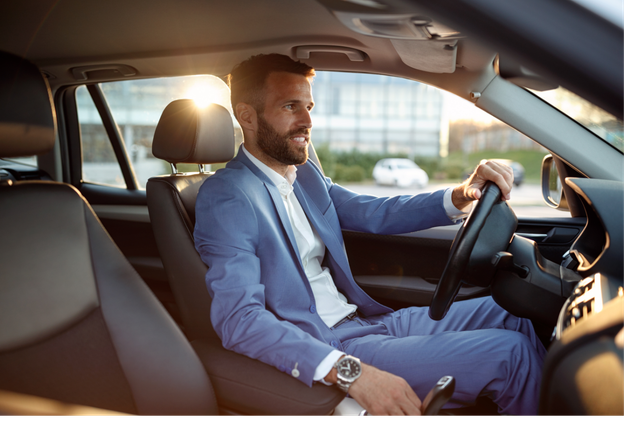 A man in a suit is sitting in the driver 's seat of a car.