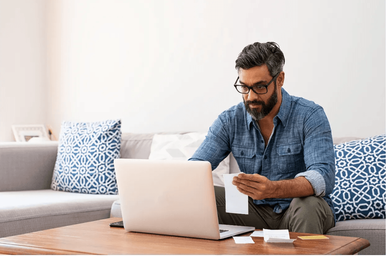 A man is sitting on a couch using a laptop computer.