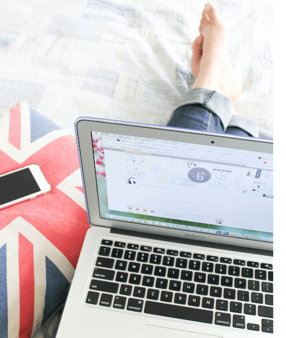 A person is sitting on a bed with their feet up and using a laptop