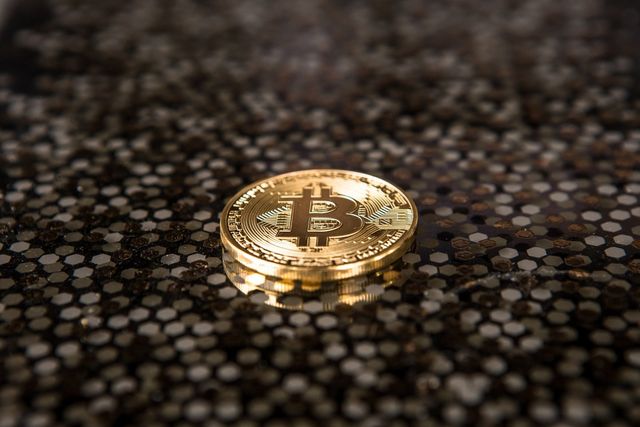 A close up of a gold coin on a black surface.