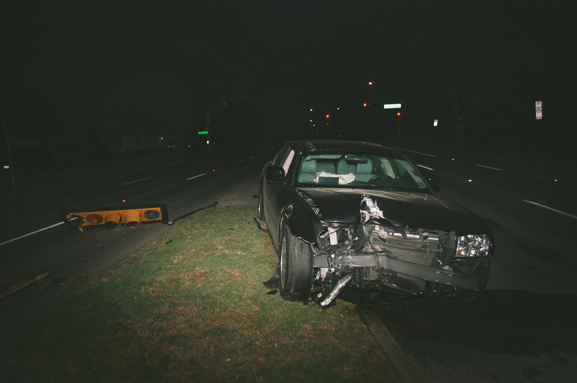 A car is sitting on the side of the road in the dark.