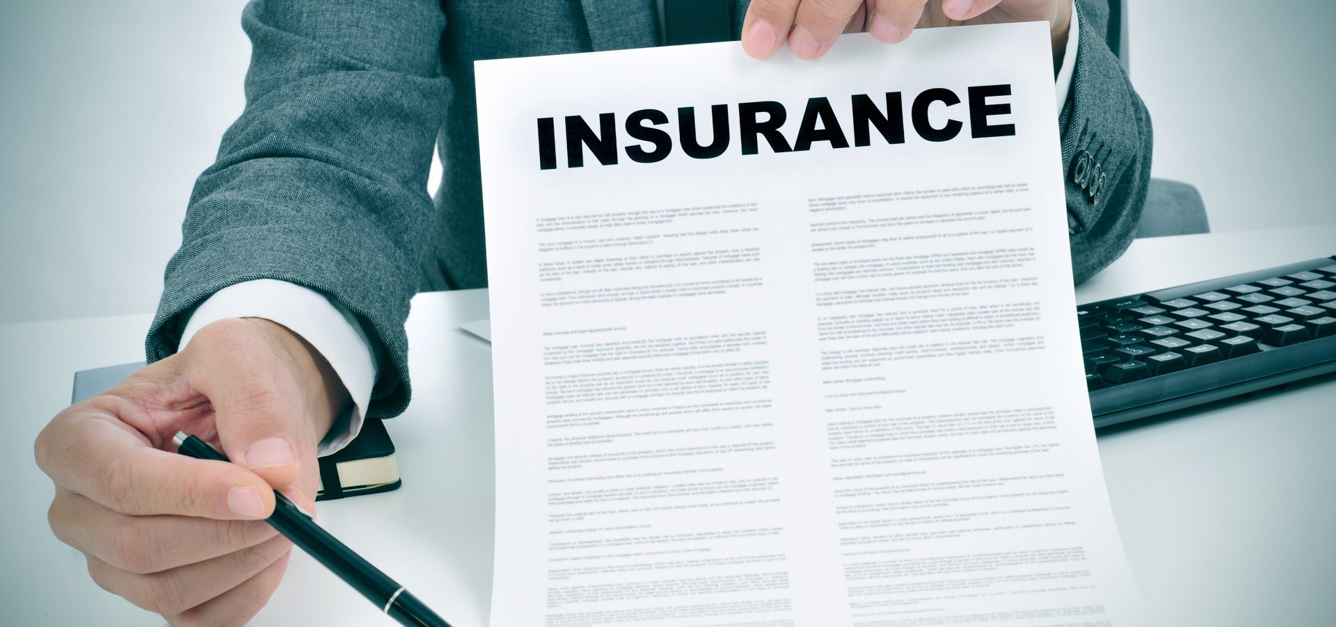 A man is holding a piece of paper with the word insurance on it.