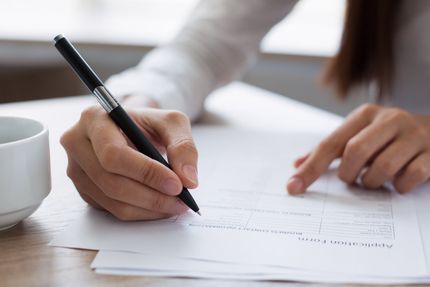 A person is writing on a piece of paper with a pen.